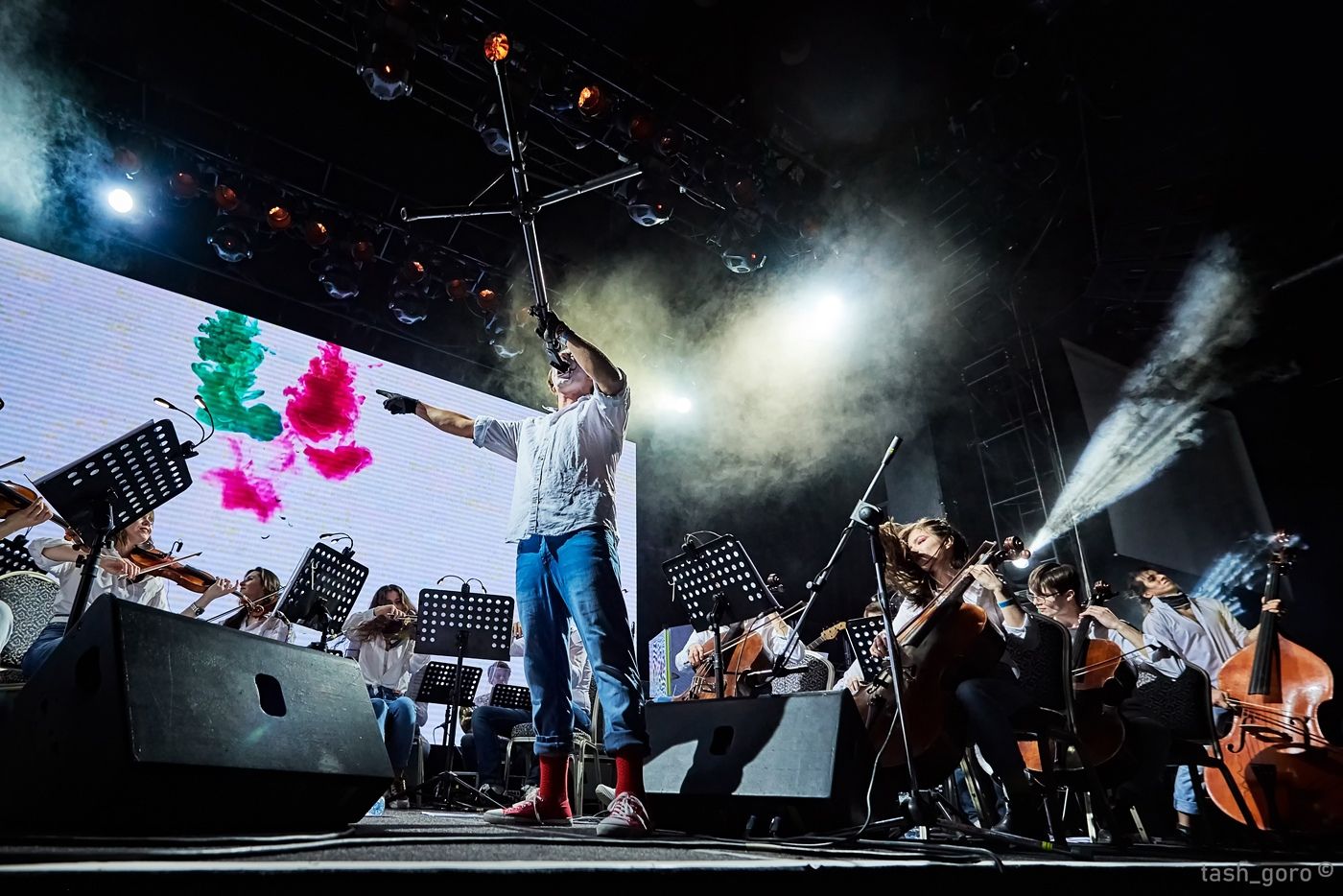Sergey Akimov conducting on stage in a white shirt
