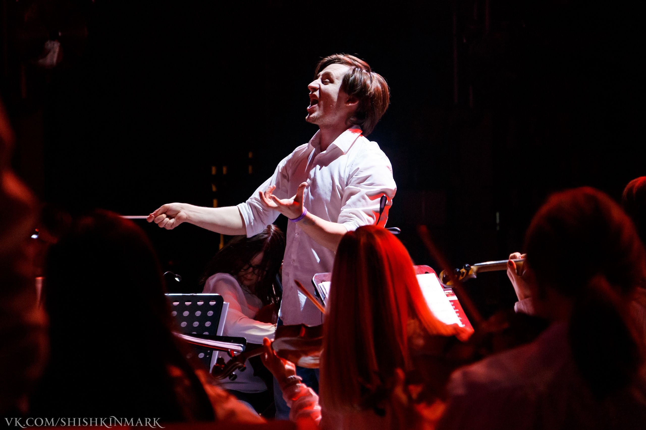 Sergey Akimov conducting in warm theatre lighting